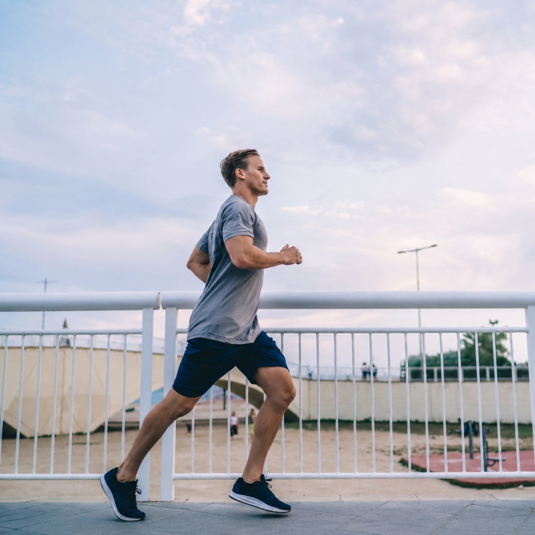 A man wearing athletic clothes running along a scenic coastal boardwalk.