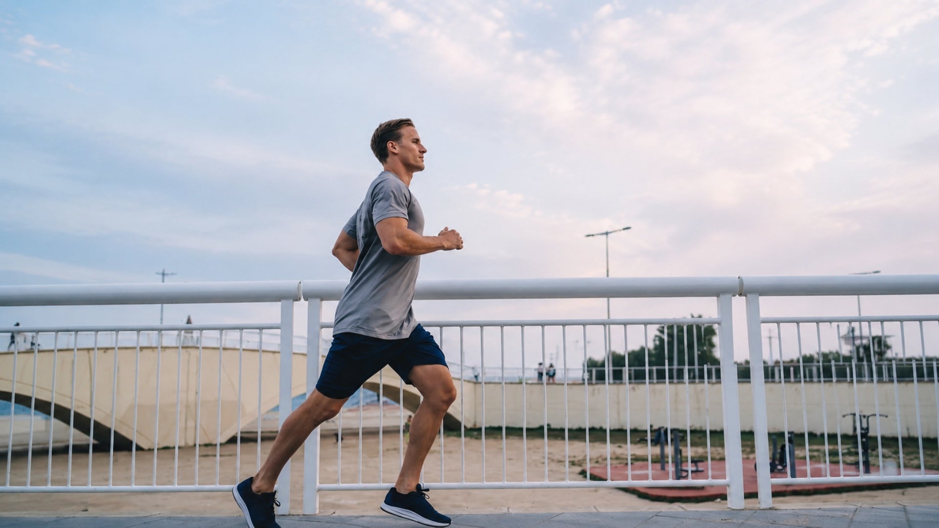 A man wearing athletic clothes running along a scenic coastal boardwalk.